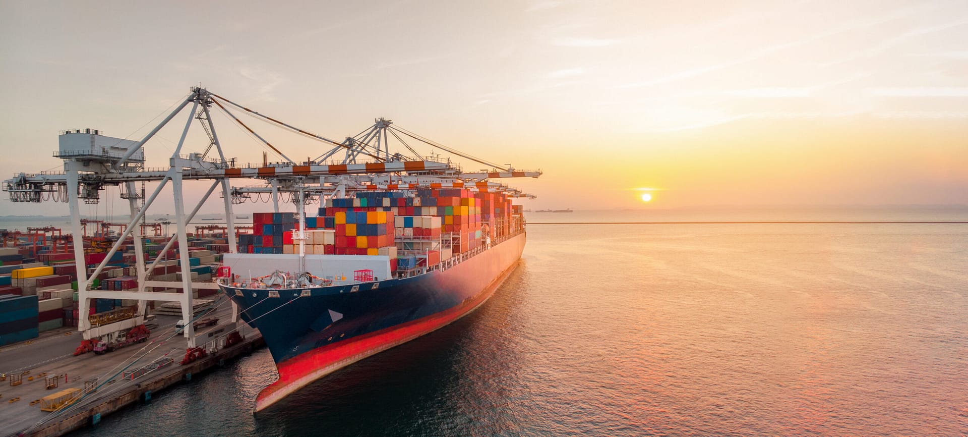 A busy international shipping port with containers being loaded onto a cargo ship